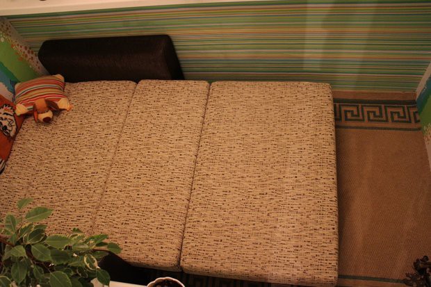 Утепленная лоджия с диваном-кроватью и роллшторами на окнах с ремонтом за 250 долларов